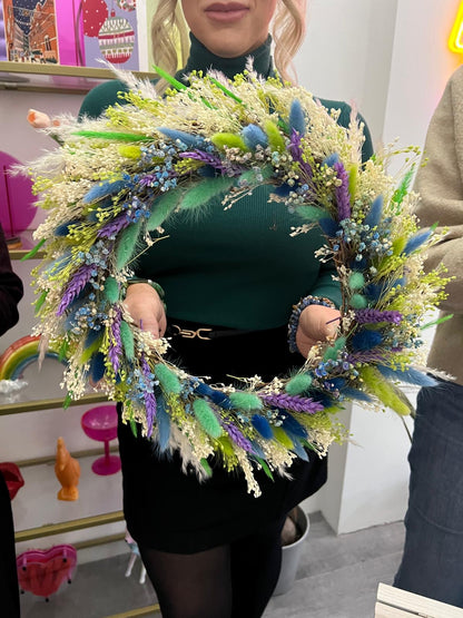 a Woman holding their own crafted green and boho coloured wreath made at a workshop hosted by The Flower Studio by Roo in Birmingham