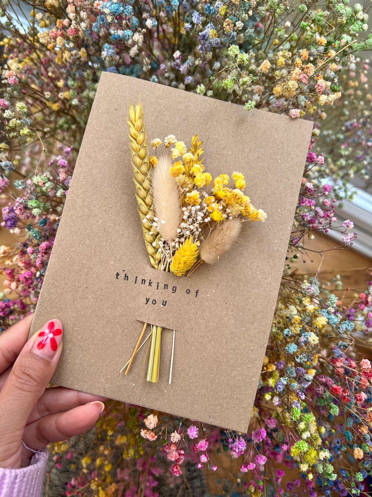 Handmade 'Thinking of You' card with dried flowers arranged in a removable slot. The flowers can be taken out and placed in a small vase, creating a lasting keepsake of care and thoughtfulness.