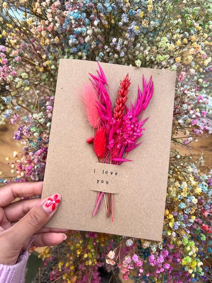 Handmade 'I Love You' card with dried flowers arranged in a removable slot. The flowers can be taken out and placed in a small vase, making it a lasting and thoughtful keepsake.