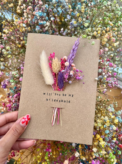 Handmade 'Will You Be My Bridesmaid?' card with dried flowers arranged in a removable slot. The flowers can be taken out and placed in a small vase, making it a meaningful keepsake for your bridesmaid proposal.